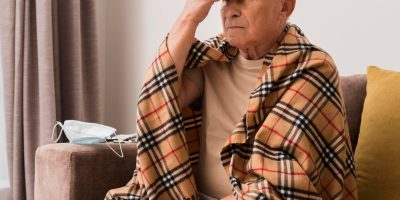 A gentle and caring caregiver interacting with an elderly person showing signs of dementia, both seated in a warm and inviting room.