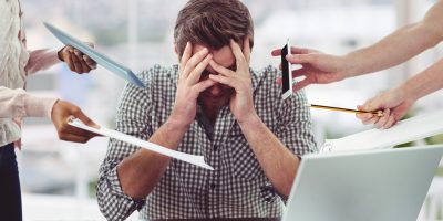 Stressed man frustrated with electronic devices in office