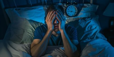 man-suffering-from-headache-turning-off-alarm-clock-bed-night_144356-99945